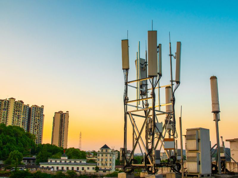 Image of a cell tower antenna against a clear sky, emitting visible electromagnetic fields, illustrating the spread of EMF in the environment